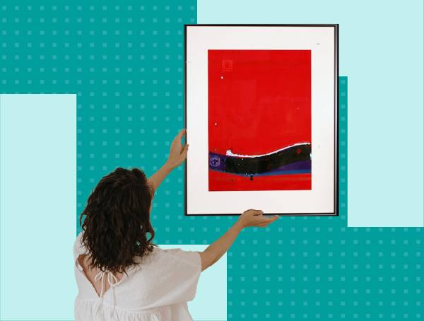 A woman hangs a piece of art she rented from the library