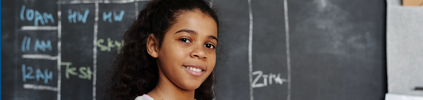 A student working at a chalkboard in their classroom.