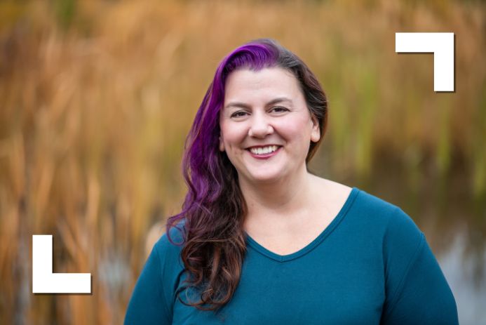 white woman with brown and purple hair wearing a green shirt looking at camera and smiling